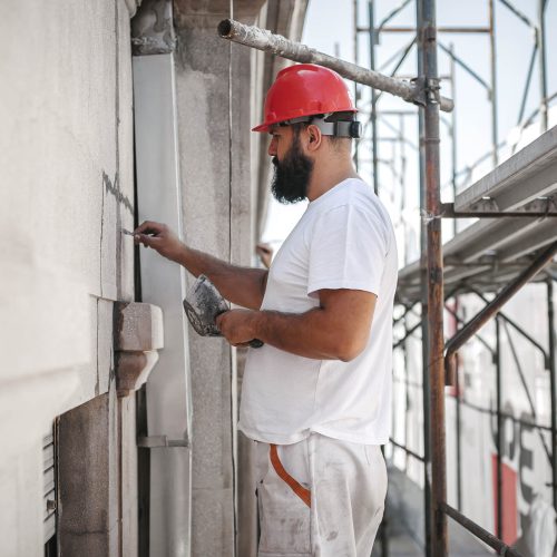 Man worker standing on scaffolding, perform work on the restorat